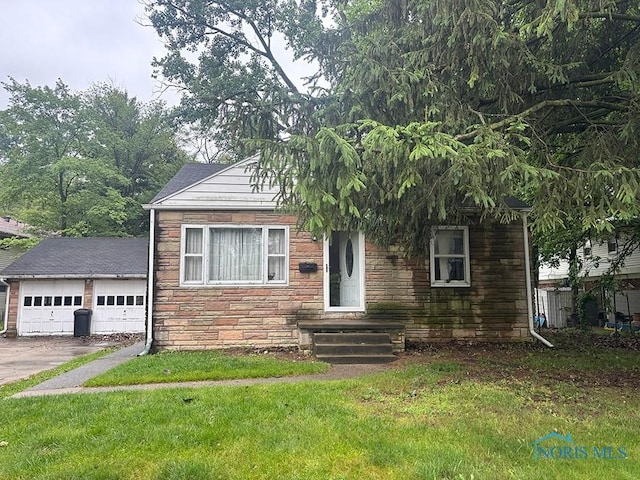 6913 Brint Rd, Sylvania, OH 43560 - view of front of home featuring stone siding, a detached garage, and a front lawn