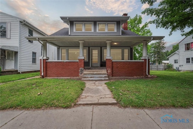 108 Western Ave, Findlay, OH 45840 - bungalow-style house with a porch, a lawn, a chimney, and brick siding