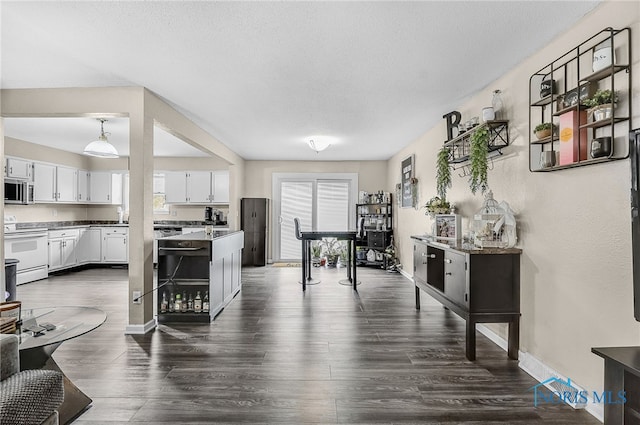 616 Normandie Blvd, Bowling Green, OH 43402 - kitchen with white range with electric stovetop, stainless steel microwave, white cabinets, dark wood finished floors, and a textured ceiling