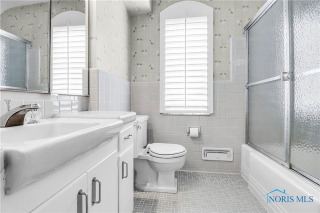 3998 W Bancroft St, Ottawa Hills, OH 43606 - bathroom featuring tile walls, wallpapered walls, healthy amount of natural light, vanity, and combined bath / shower with glass door