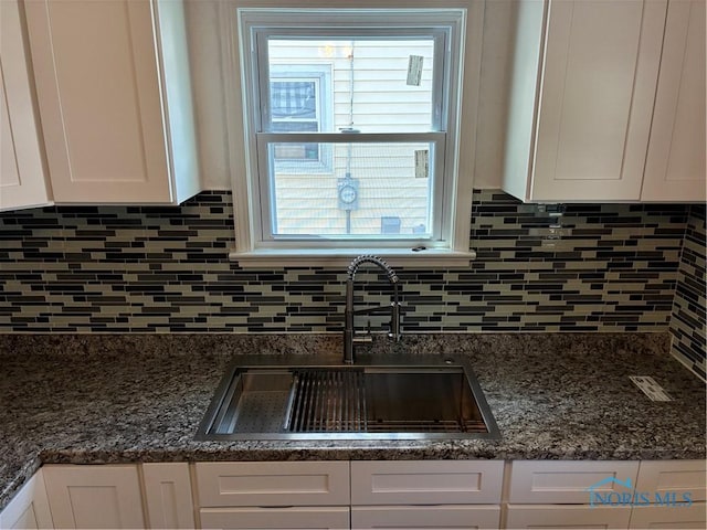 4033 Eastway St, Toledo, OH 43612 - kitchen view of white cabinetry, decorative backsplash, and dark stone countertops