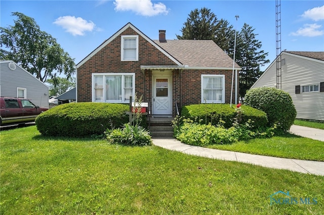 2632 117th St, Toledo, OH 43611 - bungalow-style house featuring brick siding, a front lawn, and a chimney
