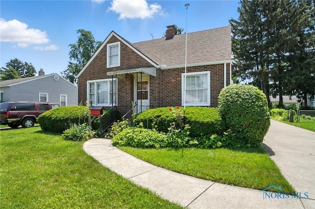 2632 117th St, Toledo, OH 43611 - bungalow with brick siding, a front yard, a shingled roof, and a chimney