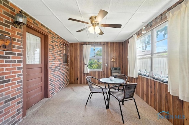 2632 117th St, Toledo, OH 43611 - carpeted dining room with ceiling fan, wooden walls, and brick wall