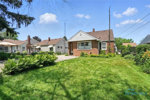 2632 117th St, Toledo, OH 43611 - view of front facade with brick siding, a front lawn, and a chimney
