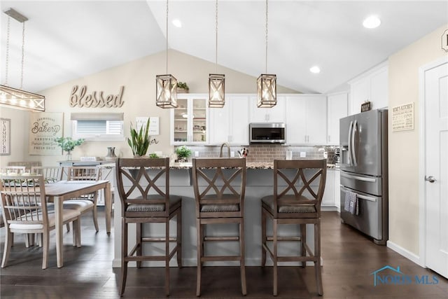 4825 Sylvan Prairie Ct, Sylvania, OH 43560 - kitchen featuring stainless steel appliances, lofted ceiling, tasteful backsplash, dark wood-style floors, and a center island with sink
