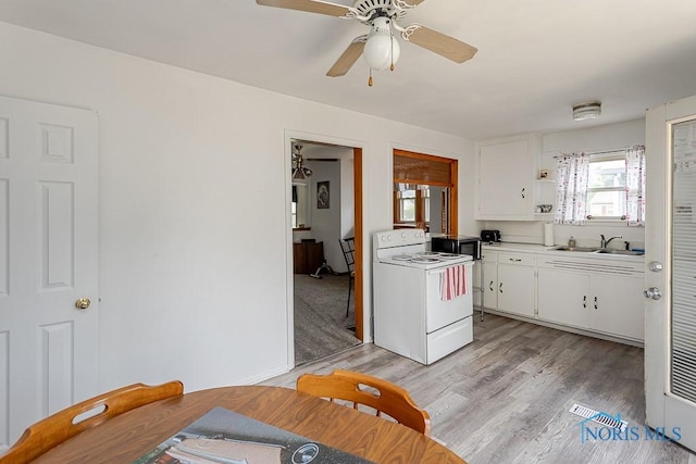 5712 Rambo Ln, Toledo, OH 43623 - kitchen with white electric range oven, ceiling fan, white cabinetry, and plenty of natural light