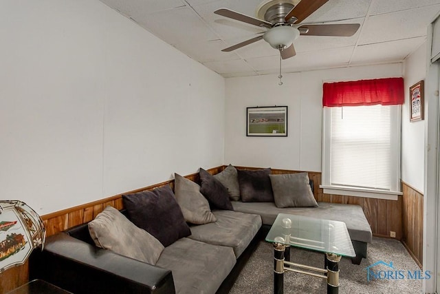 5712 Rambo Ln, Toledo, OH 43623 - carpeted living room with a paneled ceiling, wooden walls, a wainscoted wall, and a ceiling fan
