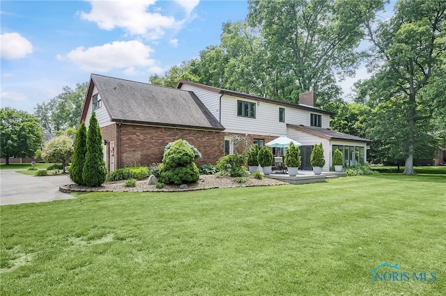 772 Fairway Ln, Wauseon, OH 43567 - view of front facade featuring brick siding, a chimney, a front yard, a patio area, and roof with shingles