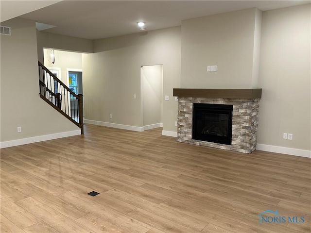 7811 Sonoma Dr, Monclova, OH 43542 - unfurnished living room with light wood-type flooring, stairs, and a fireplace