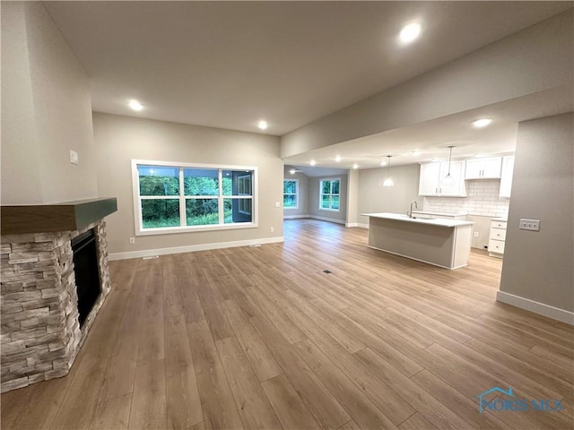 7811 Sonoma Dr, Monclova, OH 43542 - unfurnished living room with a stone fireplace, light wood-style flooring, and recessed lighting