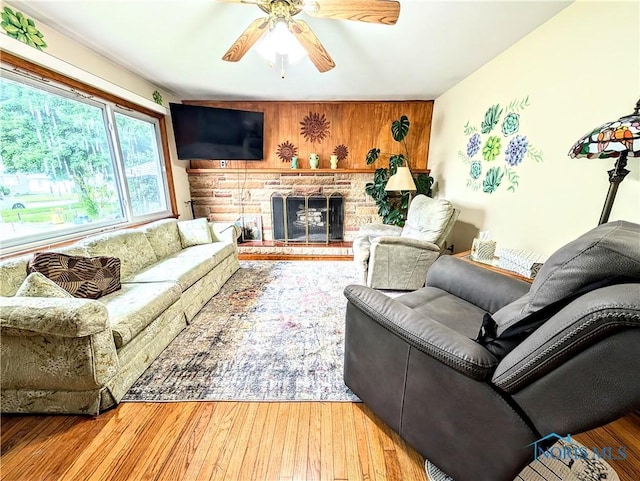 328 W Prentiss Ave, Findlay, OH 45840 - living room featuring a ceiling fan, a fireplace with raised hearth, wood walls, and wood finished floors