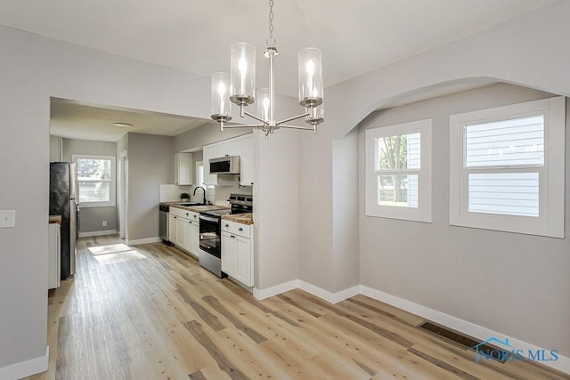 2242 Vaness Dr, Toledo, OH 43615 - kitchen with stainless steel appliances, plenty of natural light, arched walkways, and a chandelier