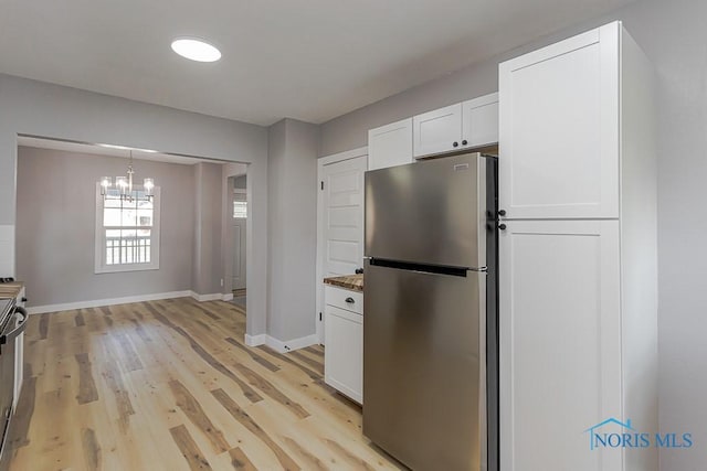 2242 Vaness Dr, Toledo, OH 43615 - kitchen featuring freestanding refrigerator, a chandelier, white cabinets, light wood-style flooring, and decorative light fixtures
