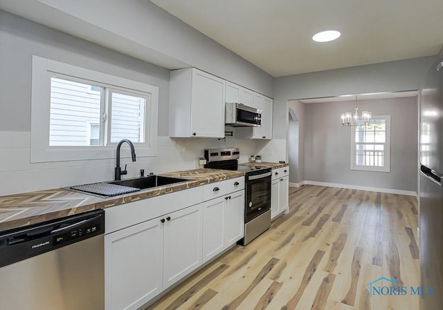 2242 Vaness Dr, Toledo, OH 43615 - kitchen with stainless steel appliances, a chandelier, wooden counters, white cabinets, and tasteful backsplash