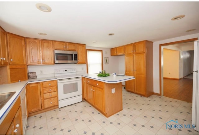 404 E Garfield Ave, Swanton, OH 43558 - kitchen with white appliances, a peninsula, light floors, light countertops, and brown cabinets