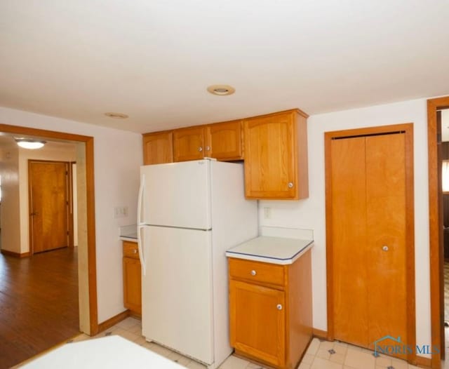 404 E Garfield Ave, Swanton, OH 43558 - kitchen with freestanding refrigerator, light countertops, and brown cabinetry