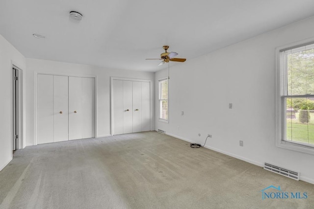 3733 Shamrock Dr, Toledo, OH 43615 - unfurnished bedroom featuring two closets, multiple windows, carpet flooring, and a ceiling fan