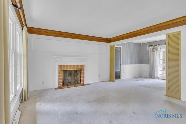 3733 Shamrock Dr, Toledo, OH 43615 - unfurnished living room with a chandelier, carpet flooring, wainscoting, and a brick fireplace