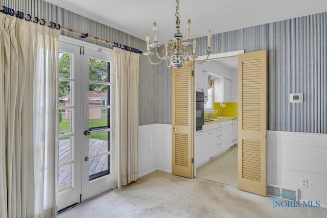 3733 Shamrock Dr, Toledo, OH 43615 - unfurnished dining area with wallpapered walls, a chandelier, wainscoting, french doors, and light colored carpet