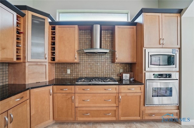 3862 Ravine Hollow Ct, Maumee, OH 43537 - kitchen featuring appliances with stainless steel finishes, wall chimney range hood, tasteful backsplash, dark stone countertops, and glass insert cabinets
