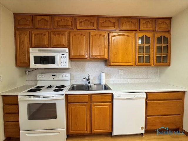 220 Rolland St, Bryan, OH 43506 - kitchen featuring white appliances, brown cabinetry, light countertops, and glass insert cabinets