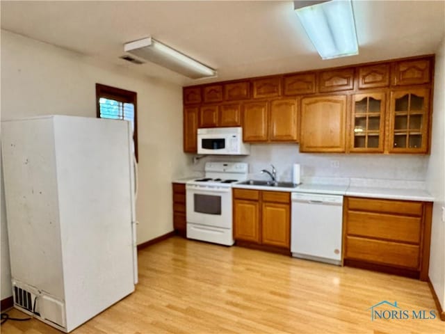220 Rolland St, Bryan, OH 43506 - kitchen with white appliances, brown cabinets, light countertops, light wood-style flooring, and glass insert cabinets