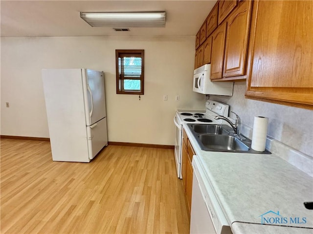 220 Rolland St, Bryan, OH 43506 - kitchen featuring white appliances, brown cabinetry, light wood finished floors, light countertops, and tasteful backsplash