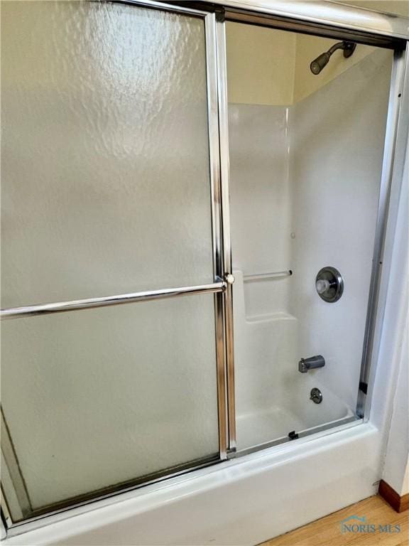 220 Rolland St, Bryan, OH 43506 - bathroom featuring wood finished floors and bath / shower combo with glass door