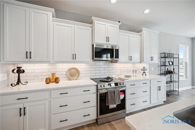 3343 Moonlit Pass, Monclova, OH 43542 - kitchen with appliances with stainless steel finishes, white cabinets, light wood-type flooring, tasteful backsplash, and recessed lighting