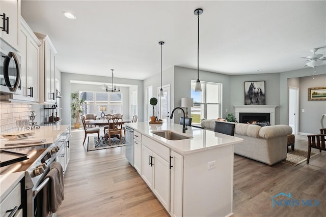 3343 Moonlit Pass, Monclova, OH 43542 - kitchen with stainless steel appliances, decorative backsplash, light wood-style flooring, white cabinetry, and light countertops