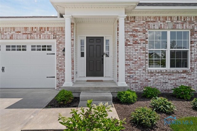 3343 Moonlit Pass, Monclova, OH 43542 - doorway to property with a garage, brick siding, and driveway