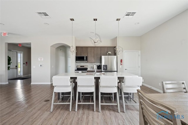 3343 Moonlit Pass, Monclova, OH 43542 - kitchen featuring stainless steel appliances, arched walkways, light wood-style flooring, a kitchen breakfast bar, and light countertops