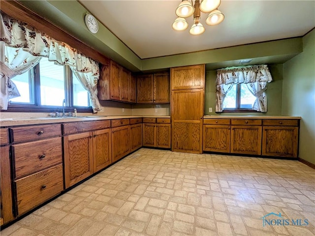 6151 The Bend Rd, Ney, OH 43549 - kitchen with brown cabinetry, brick patterned flooring, light countertops, and a chandelier