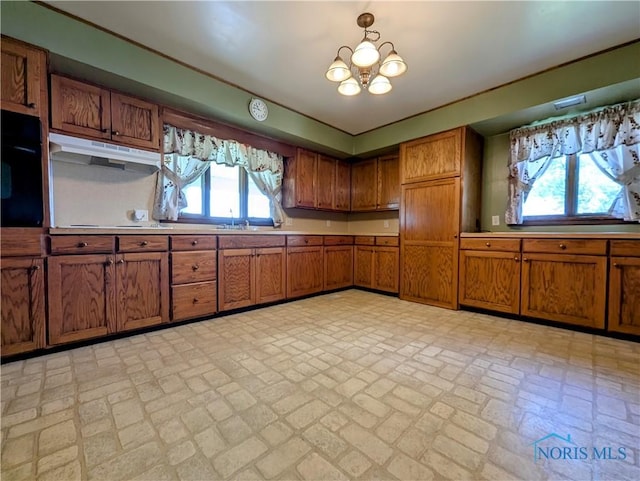 6151 The Bend Rd, Ney, OH 43549 - kitchen featuring brick patterned floors, brown cabinetry, under cabinet range hood, a chandelier, and light countertops