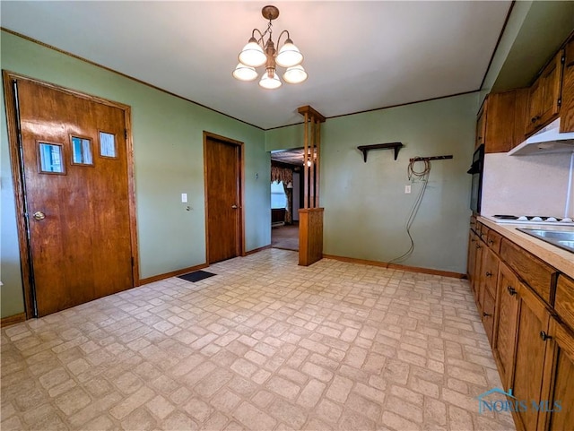 6151 The Bend Rd, Ney, OH 43549 - kitchen with brick patterned flooring, a chandelier, under cabinet range hood, brown cabinets, and light countertops