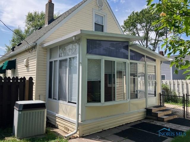 4614 290th St, Toledo, OH 43611 - view of property exterior with a sunroom, a chimney, entry steps, and uncovered parking