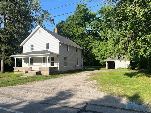 1635 S Crissey Rd, Holland, OH 43528 - view of front facade with dirt driveway, covered porch, a chimney, a front lawn, and an outdoor structure