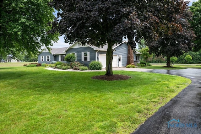 15180 Dirlam Rd, Bowling Green, OH 43402 - ranch-style house featuring concrete driveway, an attached garage, and a front yard