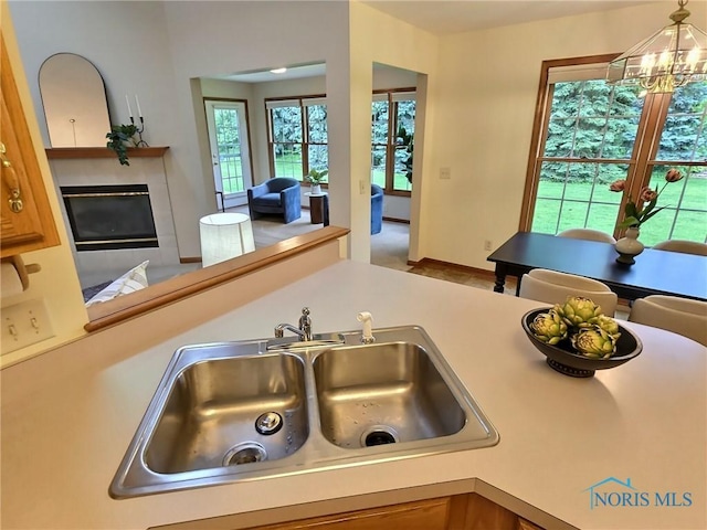 3901 Hampstead Dr Unit 3901, Sylvania, OH 43560 - kitchen featuring a chandelier, a glass covered fireplace, light countertops, and decorative light fixtures