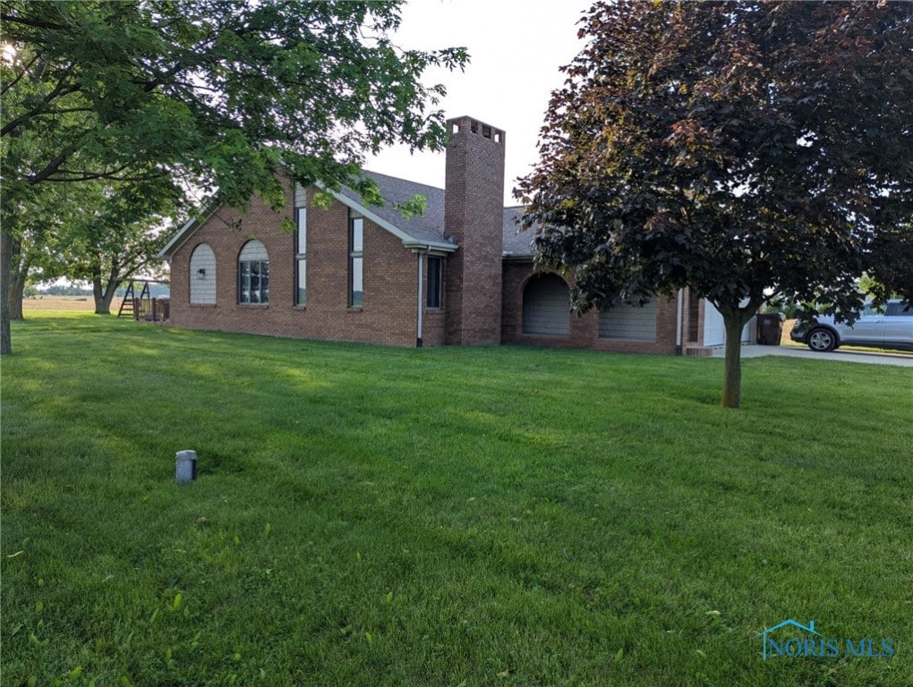 16020 County Road D, Wauseon, OH 43567 - view of front facade with a front yard, brick siding, a chimney, and a garage