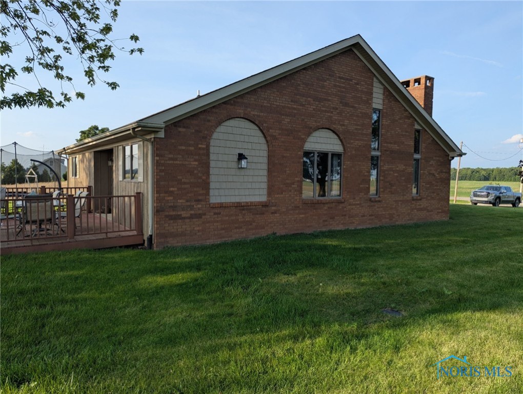16020 County Road D, Wauseon, OH 43567 - view of property exterior with brick siding, a lawn, and a chimney