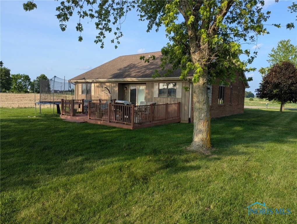16020 County Road D, Wauseon, OH 43567 - rear view of property featuring a trampoline, a deck, and a lawn