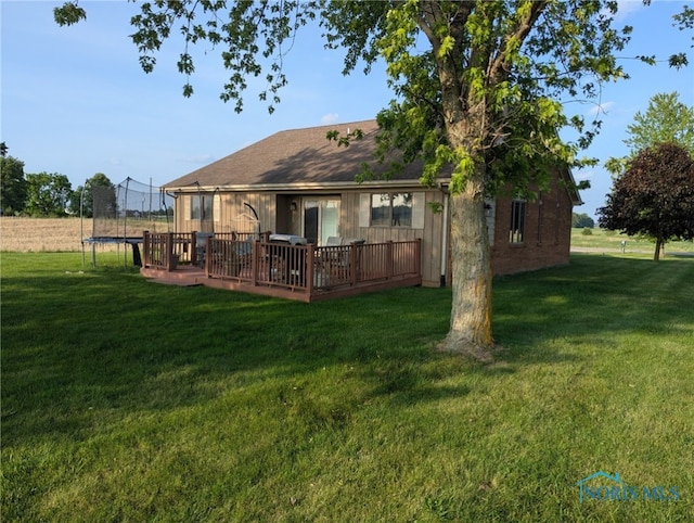 16020 County Road D, Wauseon, OH 43567 - rear view of property featuring a trampoline, a deck, and a lawn