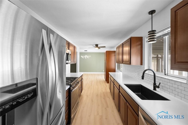 2521 Shallowford Dr, Toledo, OH 43611 - kitchen featuring appliances with stainless steel finishes, decorative backsplash, light wood finished floors, light countertops, and hanging light fixtures