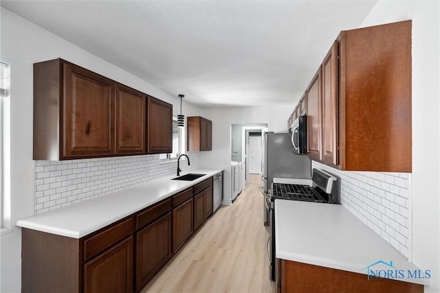 2521 Shallowford Dr, Toledo, OH 43611 - kitchen with appliances with stainless steel finishes, light wood-type flooring, backsplash, washer and clothes dryer, and light countertops