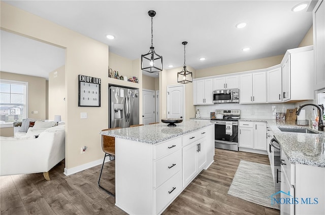 5352 Brint Crossing Blvd, Sylvania, OH 43560 - kitchen with stainless steel appliances, a kitchen island, wood finished floors, white cabinets, and recessed lighting