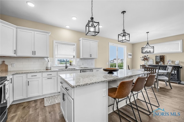 5352 Brint Crossing Blvd, Sylvania, OH 43560 - kitchen with a kitchen island, white cabinetry, backsplash, light wood finished floors, and hanging light fixtures