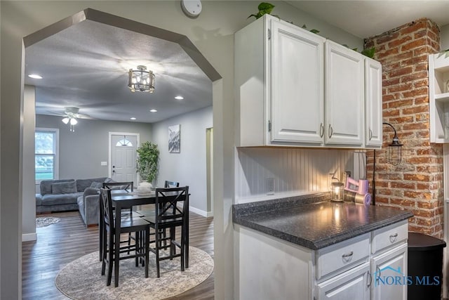 525 Western Ave, Findlay, OH 45840 - kitchen with a ceiling fan, dark countertops, white cabinets, wood finished floors, and arched walkways