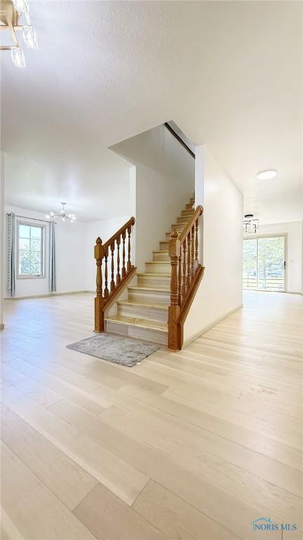 1303 Finch Dr, Bowling Green, OH 43402 - stairs featuring a chandelier and wood finished floors